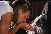 Mädchen trinkt Wasser am Brunnen