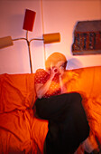 Junge Frau auf Sofa, lacht beim Telefonieren