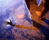Füsse einer Frau im See und Spiegelung auf der Wasseroberfläche, Schweden