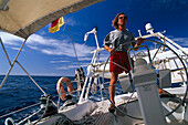 Man behind the wheel of a sailing boat under blue sky, St. Vincent and The Grenadines, Caribbean, America