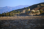 Buildings and palm trees in front of a mountain in the desert, Furnace Creek Inn, Death Valley California, USA