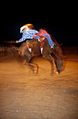 Cowboy auf Bronco beim Rodeo, Amateur-Rodeo, nachts in Lubbock, Texas