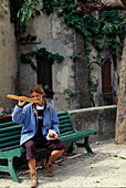 Frau auf Parkbank isst Baguette, Calonge, Cassis Frankreich