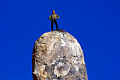 Rock climber standing on top of a summit, Hercules Finger, High Desert, California, USA