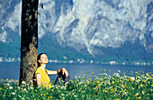 Woman relaxing under tree at Traunsee, Salzkammergut, Austria