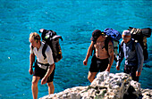 Three hikers walking along the cliff, coastal landscape, Mallorca, Balearic Islands, Spain