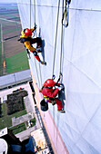 Two workers secured with ropes working on vertical metal surface, renovation works, Duernrohr power plant, Zwentendorf an der Donau, Lower Austria