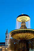Illuminated fountain in front of Ludwigskirche and University, Ludwigstrasse, Munich, Bavaria, Germany