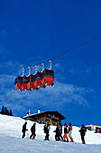 Group of skiers on slope, gondola lift Kohlmaisbahn passing, Saalbach-Hinterklemm, Salzburg (state), Austria