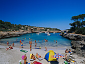 People sunbathing on the beach at Cala de Sanau, near Porto Colóm, Mallorca, Spain