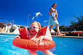 Mädchen mit Schwimmflügeln und Schimmreifen im Pool, Mallorca