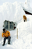 Man and dog in front of a snowed in mountain hut, Areskutan, Are, Sweden