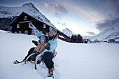 Woman and child sitting on a sledge, Gorfenspitze and Ballunspitze in the background, Galtuer, Tyrol, Austria