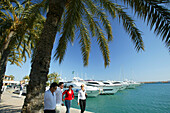 People walking along the promenade, Yachts in Puerto Portals harbour, Majorca, Balearic Islands, Spain