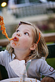 Girl eating spaghetti, pasta sauce on face, side view