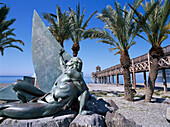 Skulptur und Palmen im Sonnenlicht an der Küste, La Herradura, Costa del Sol, Provinz Granada, Andalusien, Spanien, Europa