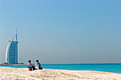 Blick auf ein Paar am Strand und das Hotel Burj al Arab, Dubai, Vereinigte Arabische Emirate, Vorderasien, Asien