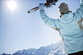 Frau hält Ski nach oben, Kühtai, Hohe Mut und Gaißkogel im Hintergrund, Kühtai, Tirol, Österreich