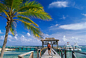 Man walking along a wooden jetty, excursion boat in the background, Brac Reef Resort, Cayman Brac, Cayman Islands, Caribbean