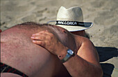 Man sunbathing on the beach with a hat over his head, Beach holiday, Majorca, Balearic Islands, Spain