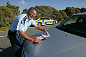 Policeman drawing a speeding ticket, Highway 6, West Coast, South Island, New Zealand, Oceania