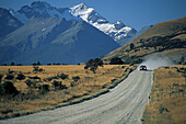 Landstrasse mit Auto vor schneebedeckten Bergen, Central Otago, Südinsel, Neuseeland, Ozeanien
