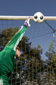 Young goalkeeper jumping for ball