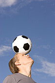Young soccer player juggling ball on his head