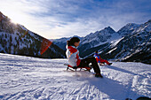 Zwei Personen fahren Schlitten in den Bergen, Staller Sattel, Antholz, Pustertal, Südtirol, Italien, Europa