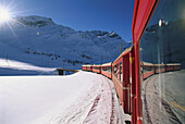 Rhätische Bahn fährt durch Winterlandschaft. Engadin, Schweiz, Europa