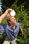 Man pouring water over his head during a hiking tour, Alps, Hocheck, Bavaria, Germany