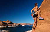 Man climbing up rock face, Lake Powell, Arizona, USA