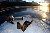 Three people watching the sunset over Lake Silvaplana, Grissons, Switzerland