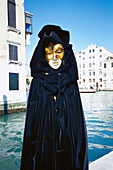 Maskierte Person in Verkleidung vor einem Kanal, Venedig, Italien, Europa