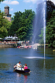 Menschen im Ruderboot in einem Teich mit Fontäne, Kurpark, Wiesbaden, Hessen, Deutschland, Europa