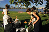 Bride and party in city park, West Australien, Australien, wedding party at riverside in front of Perth city skyline Hochzeitsgruppe in Stadtpark am Fluss