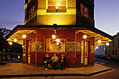 Palisade Hotel, pub in the Rocks, Sydney, Australien, NSW, Three men sitting in front of pub drinking beer after work in the historic quarter called The Rocks, Vor der beleuchtete Kneipe sitzen drei Männer und trinken Bier am Feierabend
