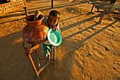 Child drinks water from terracotta pot, Junge trinkt Wasser aus Tontopf, Wasserbehaelter aus Ton, typisch