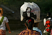 Women balancing plastic bag on head, Frau balanciert eine volle Plastikbeutel auf dem Kopf