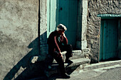Old man is sitting on stairs in the Provence, France