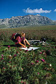 Female mountainbiker reading map on a meadow, Abruzzo, Italy