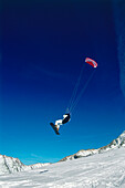 Mann springt beim Snowkiting, Lermoos, Lechtaler Alpen, Tirol, Österreich