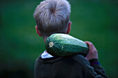Boy carring zucchini on shoulders, Deutschland