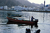 Ein Mann fährt in einem Fischerboot im Hafen, Maskat, Oman