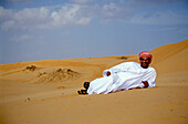 Man lying in the sand at the desert, Sultanat Oman, Middle East, Asia