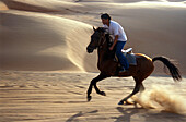 Junger Mann reitet ein Pferd in der Wüste, Sultanat Oman, Vorderasien, Asien