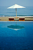 Ein Sonnenschirm spiegelt sich im Pool des Chedi Hotel, Maskat, Oman