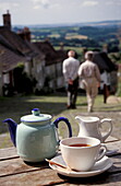 Teatime, Teekanne und Tasse vor steiler Strasse, Gold Hill, Shaftesbury, Dorset, England, Grossbritannien, Europa