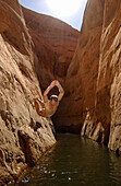 Man jumping off a cliff at Lake Powell, Cliff dive, Secret Canyon, Lake Powell, Utah, Arizona, USA