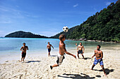 Junge Männer spielen Fußball am Strand von Ko Butang, Thailand